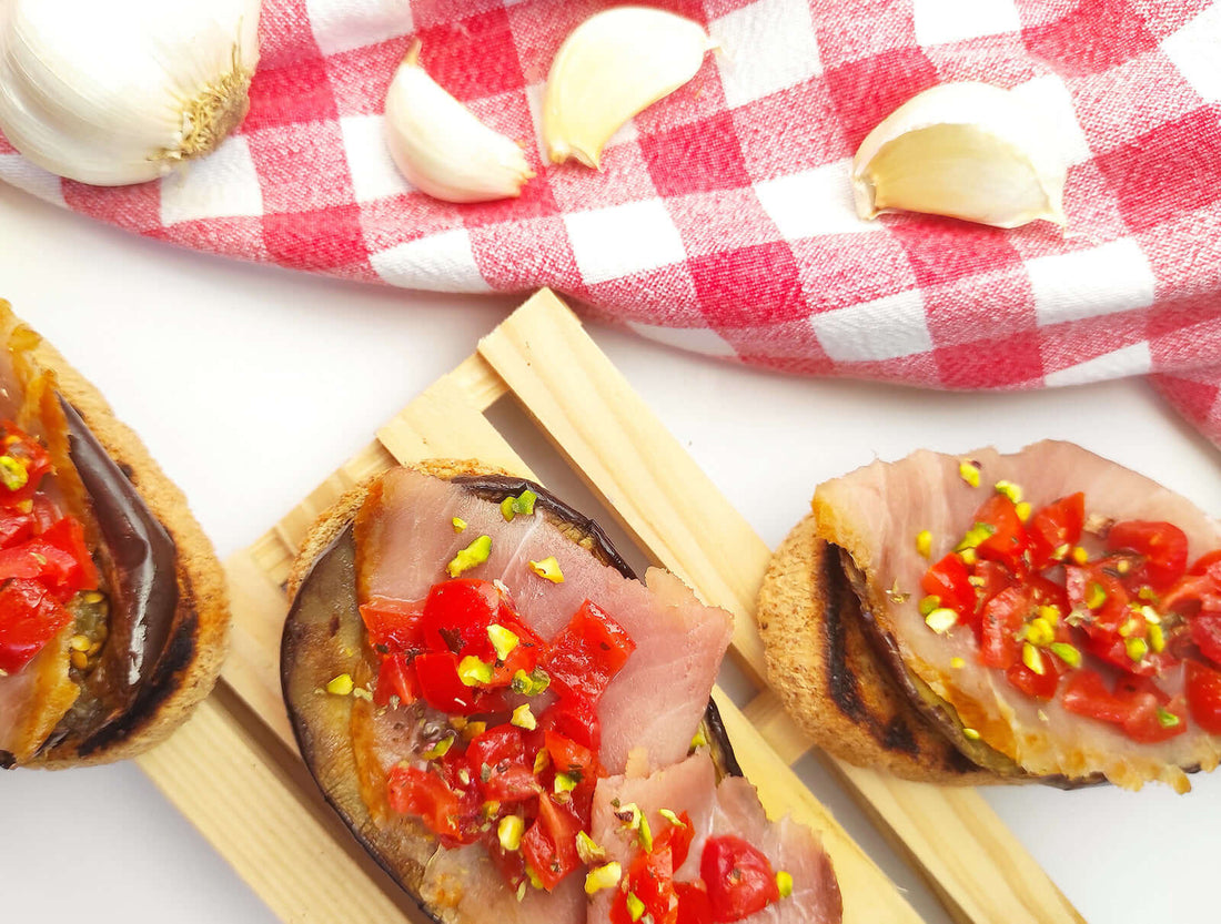 Bruschette con pesce spada affumicato, melanzane grigliate, pomodorini e pistacchi