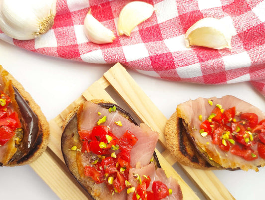 Bruschette con pesce spada affumicato, melanzane grigliate, pomodorini e pistacchi